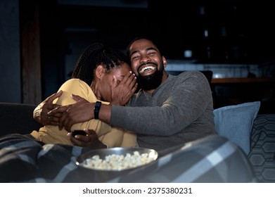 African American couple watching a movie at home over a streaming cable service. Movie night. Woman is very emotional - Powered by Shutterstock