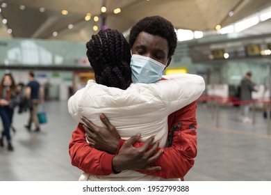 African American couple wear medical face masks hugging, embrace each other within the new normality at airport terminal. Black man hug lovely girlfriend after long separation due to pandemic Covid-19