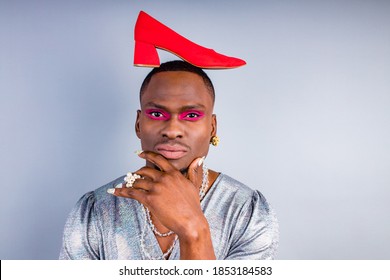 African American Cross Dressing Trans Drag Queen Holding A Red Shoe In Studio White Wall