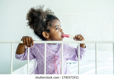 African American Cute Baby Girl  Holding Eating Ice Cream  On Bed In Bedroom