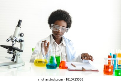 African american cute little boy student child learning research and doing a chemical experiment while making analyzing and mixing  liquid in glass at science class on the table.Education - Powered by Shutterstock