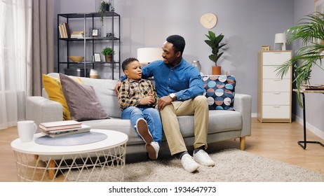 African American cute little boy child speaking with caring dad in good mood telling how was his day while sitting on sofa in house in living room. Father son relations. Family time, leisure concept - Powered by Shutterstock