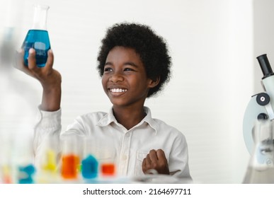 African american cute little boy student child learn science research and doing a chemical science experiment making analyzing and mix liquid in test tube on class at school