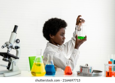 African american cute little boy student child learn science research and doing a chemical science experiment making analyzing and mix liquid in test tube on class at school