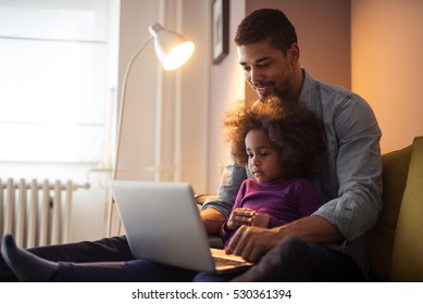 African American Dad And His Daughter Using Laptop Together.