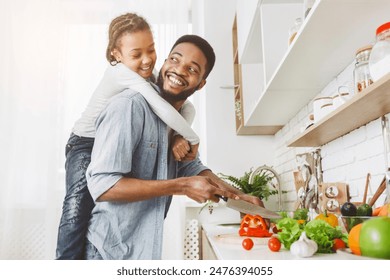 African american dad and his playful daughter having good time at kitchen, girl jumped on father from behind, free space - Powered by Shutterstock