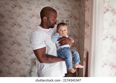 African American Dad Holds His Son Little Baby In Arms At Home, Child Looks At Camera