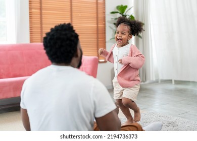 African American Daughter Running And Hug Father In The Living Room With Smile. Multi-ethnic Diverse Friendly Family At Modern Home Spending Time Together. Dad Embracing Kid Cuddling. Soft Focus