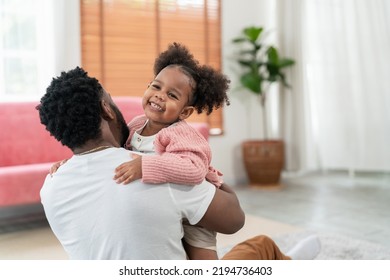 African American Daughter Running And Hug Father In The Living Room With Smile. Multi-ethnic Diverse Friendly Family At Modern Home Spending Time Together. Dad Embracing Kid Cuddling. Soft Focus