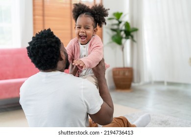 African American Daughter Running And Hug Father In The Living Room With Smile. Multi-ethnic Diverse Friendly Family At Modern Home Spending Time Together. Dad Embracing Kid Cuddling. Soft Focus