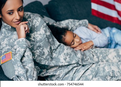 african american daughter sleeping on mother in military uniform at home - Powered by Shutterstock