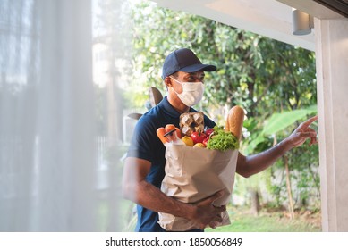 African American Delivery Man Wearing Protective Face Mask Holding Grocery Paper Bag Of Healthy Food With Fresh Vegetables, Milk, Bread. 