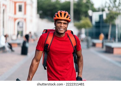 African american delivery man wearing safety helmet smiling and looking at camera in the street. - Shutterstock ID 2222311481