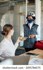 African American Delivery Woman Wearing Protective Face Mask While Delivering Food To A Businesswoman In The Office.