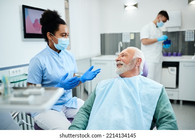 African American dental assistant communicating with senior patient during dental procedure at dentist's office. - Powered by Shutterstock