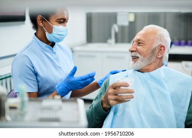 African American dental nurse communicating with senior patient during dental procedure at dentist's office.  - Powered by Shutterstock