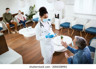 African American Dental Nurse Communicating With Patient While Using Digital Table In Waiting Room At Dental Clinic. 