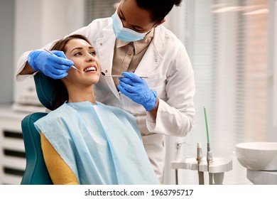 African American dentist examining teeth of her female patient during appointment at dental clinic. Focus is on young woman. - Shutterstock ID 1963795717