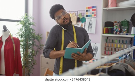 African american designer taking notes in a tailor shop with colorful fabrics and mannequin in the background. - Powered by Shutterstock