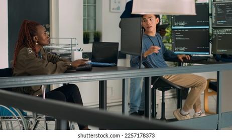 African american developer with disability working with programming language on terminal window. IT engineer in wheelchair using html script to develop new program interface on computer.