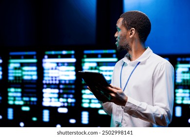 African american IT developer using tablet to audit energy consumption across server parts. Programmer making sure data center hardware temperature sensors are in flawless working condition