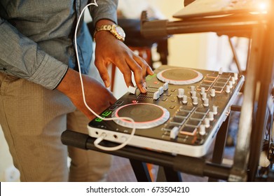 African American Dj In Huge White Headphones Creating Music On Mixing Panel.