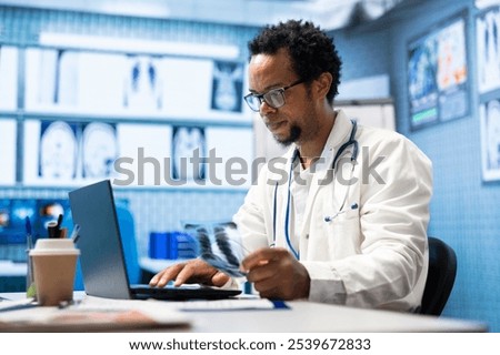 African american doctor analyzing radiography test results for recovery plan, consulting healthcare records and x ray scans for the right diagnosis. Licensed radiology expert at private clinic.