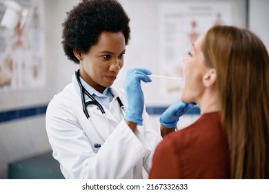 African American doctor examining woman throat during medical appointment at doctor's office.