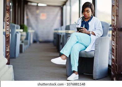 African American Doctor Female With Stethoscope Looked At Phone And Sitting On Clinic.