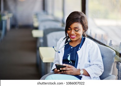 African American Doctor Female With Stethoscope Looked At Phone And Sitting On Clinic.