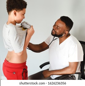 An African American Doctor With His Mixed Preteen Male.
A Cute Black Paediatrician Examining His Young Mixed Preteen Boy Patient With A Stethoscope.