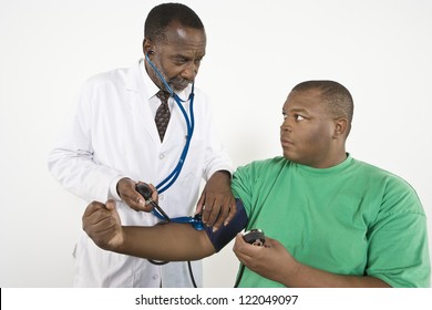 An African American doctor looking at obese patient while checking blood pressure in clinic