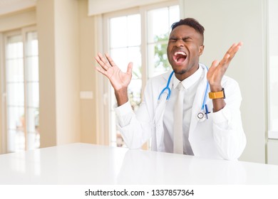 African american doctor man at the clinic celebrating mad and crazy for success with arms raised and closed eyes screaming excited. Winner concept - Shutterstock ID 1337857364