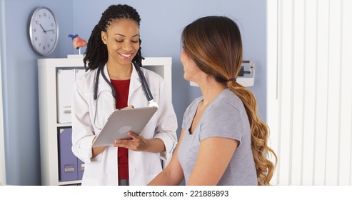 African American Doctor With Tablet Computer Talking To Asian Patient