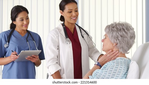 African American Doctor Talking To Elderly Woman Patient With Nurse