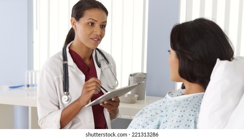 African American Doctor Talking To Hispanic Patient In Bed