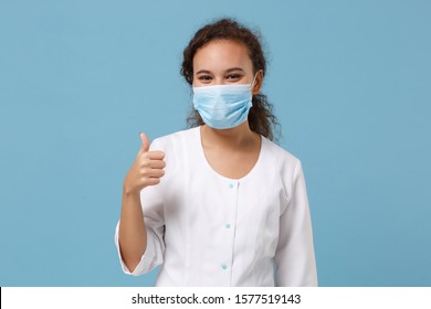 African american doctor woman isolated on blue background. Female doctor in white medical gown, sterile face mask showing thumb up. Healthcare personnel health medicine concept. Mock up copy space - Powered by Shutterstock