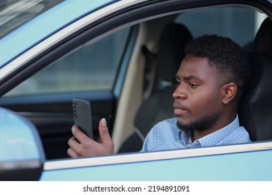 African American Driver With Phone Sitting At Car Steering Wheel.