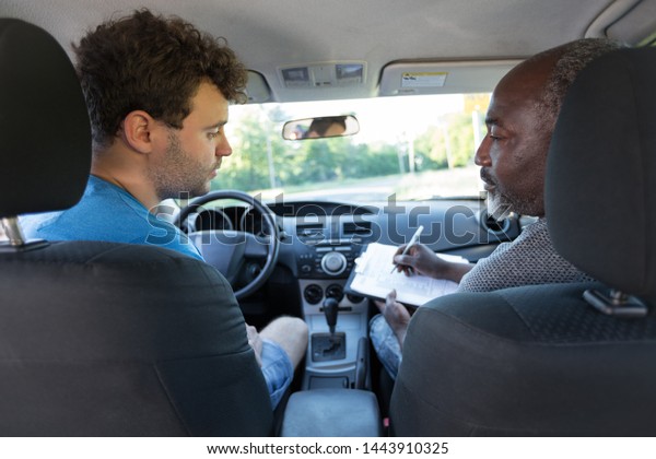 African American Driving Instructor And\
Caucasian Student In The Front Of The\
Car.