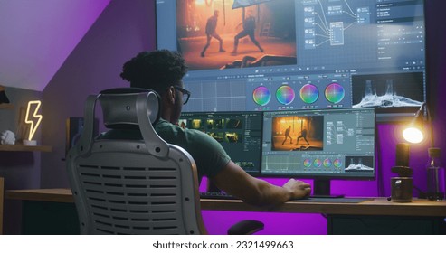 African American editor makes color correction, edits action movie, works at home. Software interface with RGB tools and wheels on computer and big digital screen. Concept of film post production. - Shutterstock ID 2321499663
