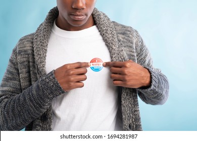 African american election voter wears I voted today pin after voting in USA, blue background