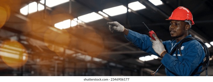 african american electrician worker with electric wire using and talking to walkie-talkie radio in factory with copy space - Powered by Shutterstock