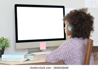 African American Elementary School Kid Girl Wearing Headphones Virtual Distance Learning Online Looking At Mock Up White Blank Computer Screen Remote Digital Elearning At Home. Over Shoulder View