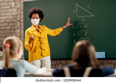 African American elementary school teacher holding mathematics class and wearing protective face mask due to coronavirus pandemic.  - Shutterstock ID 1820908544
