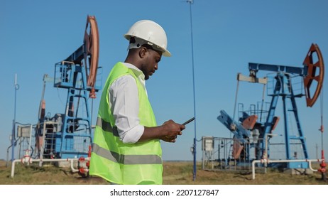 African American engineer controls development of crude oil by jack-pumps. Black man types information for future report about production