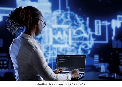 African american engineer updating AI systems, writing intricate binary code scripts on laptop. Tech support using programming to upgrade artificial intelligence simulation model - Shutterstock ID 2374220347