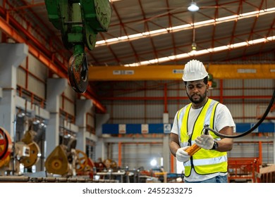 African American engineer worker is using overhead crane hoist to carry raw materials in the metal sheet manufacturing factory for heavy industry - Powered by Shutterstock