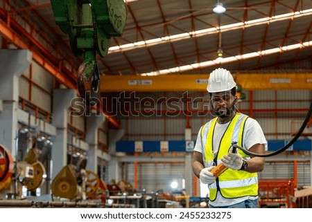 African American engineer worker is using overhead crane hoist to carry raw materials in the metal sheet manufacturing factory for heavy industry
