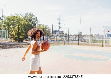 African American ethnic sporty woman having fun. Stylish cool teen girl gathering at basketball court, playing basketball outdoors