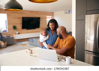 African American Family With Baby Daughter Using Laptop To Check Finances At Home